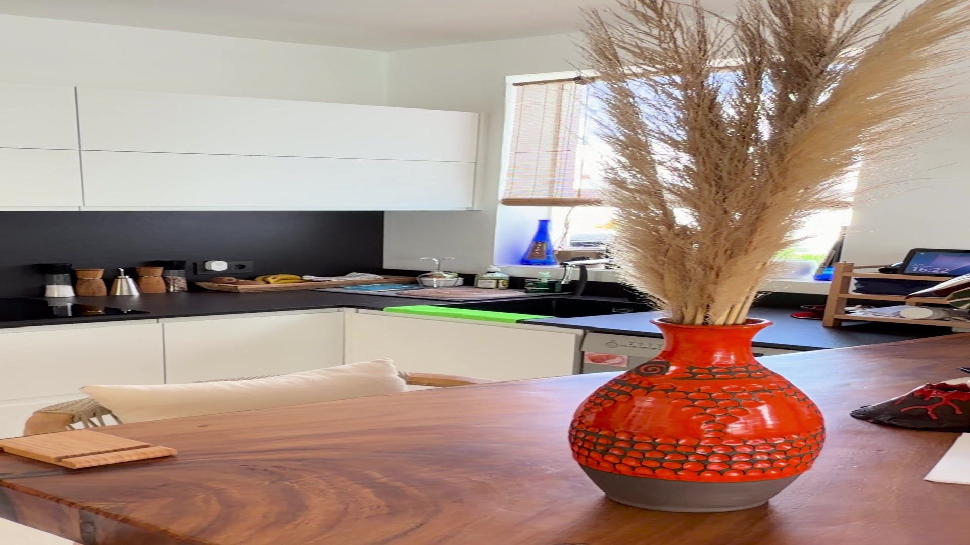 Cocina principal con encimera blanca curva y vaso decorativo