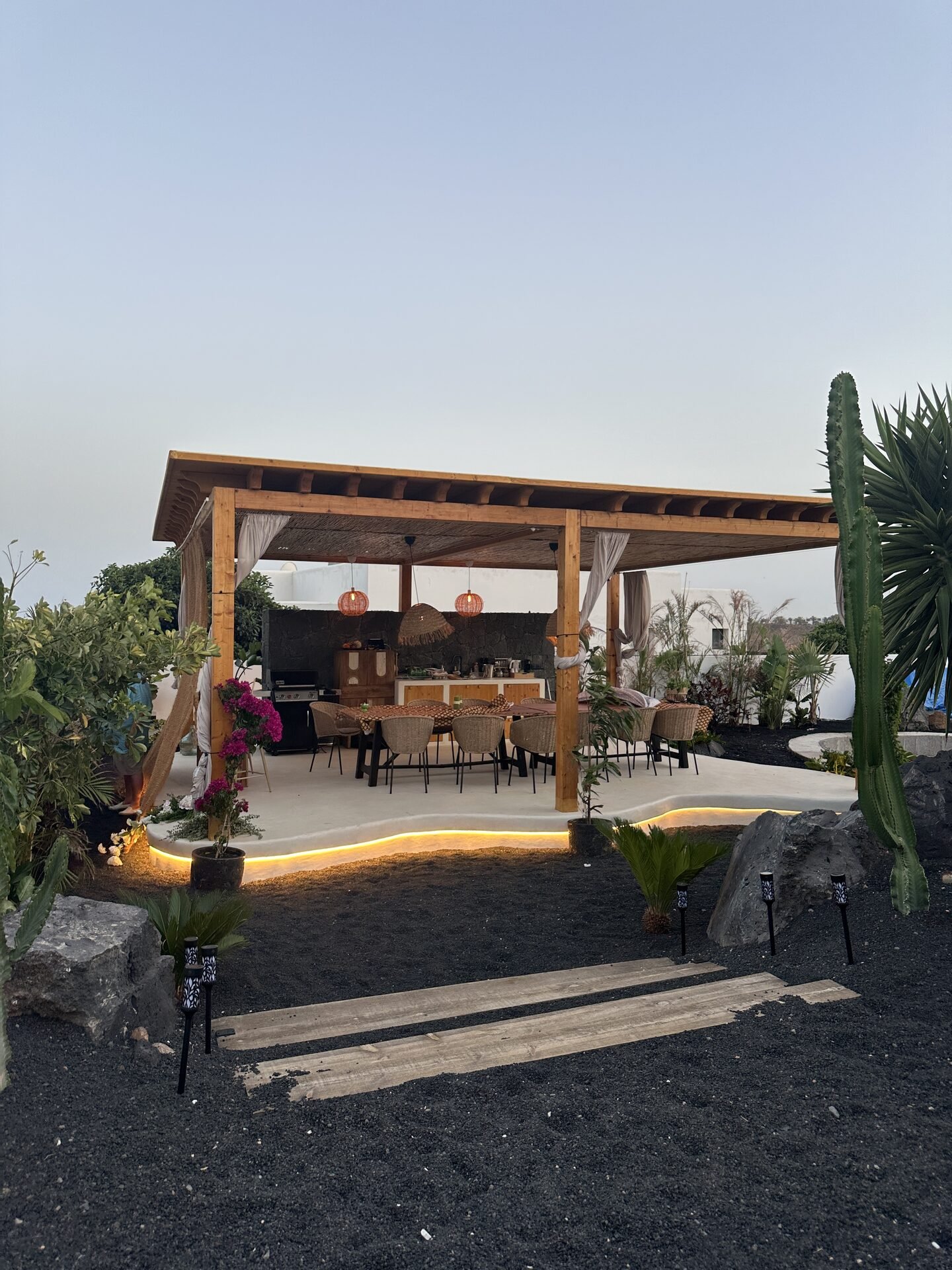 Pérgola nocturna iluminada con mesa de cena