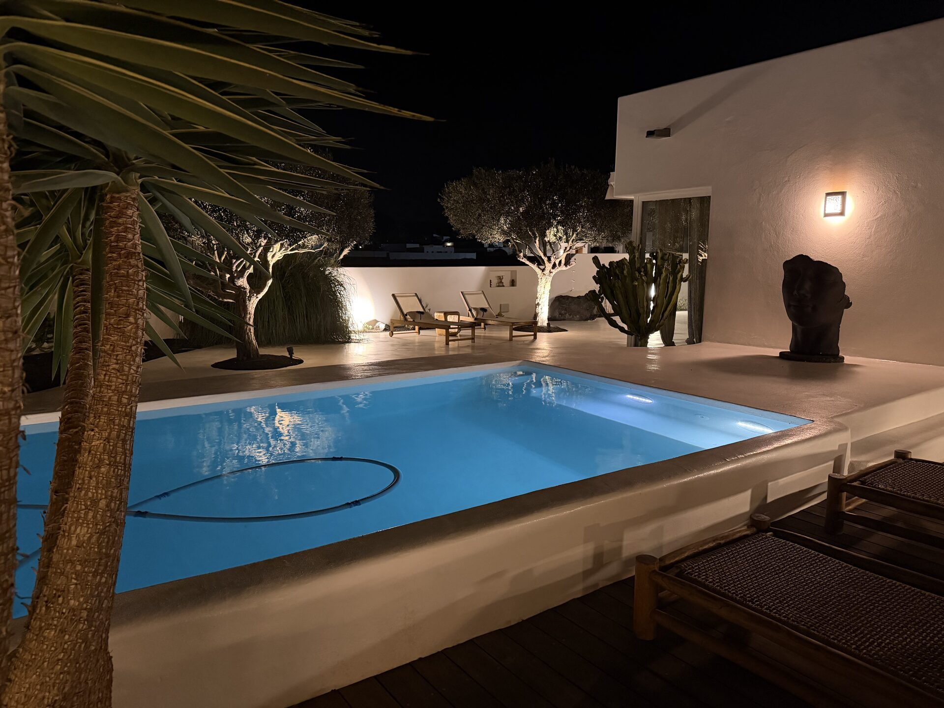 Piscina iluminada de noche con escultura